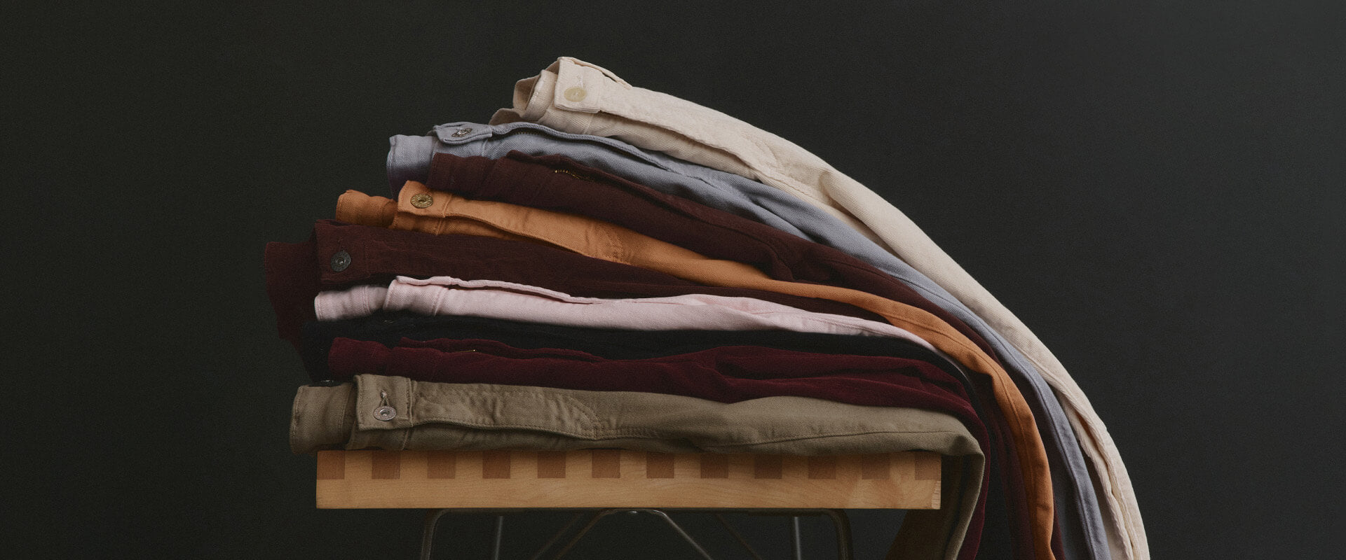 Stack of folded clothes on a wooden board against a dark background