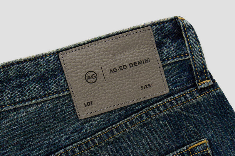 Close-up of AG Ed Denim label on a blue denim fabric background