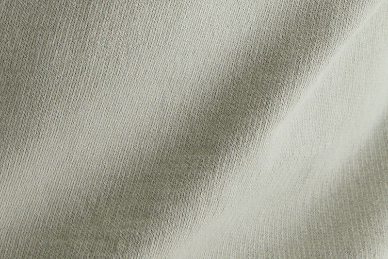 A close-up of light-colored, textured knit fabric showing S twist and Z twist.