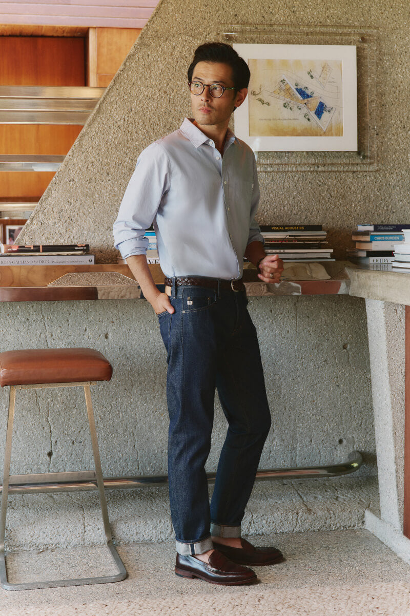 Man in blue shirt and blue jeans standing in office