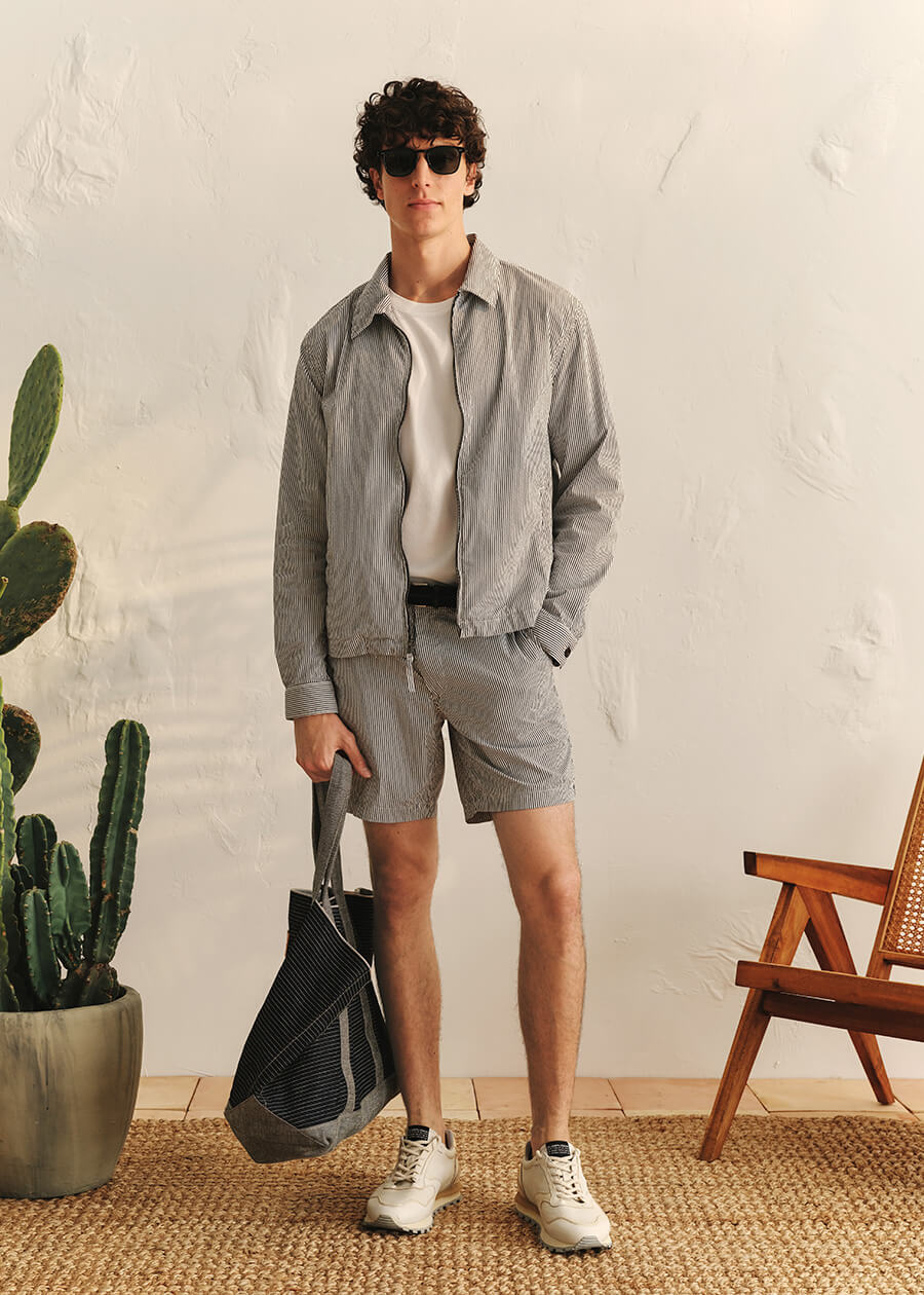 Man in grey jacket and shorts standing in room