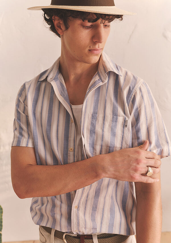 Man in striped shirt with a hat in front of white background