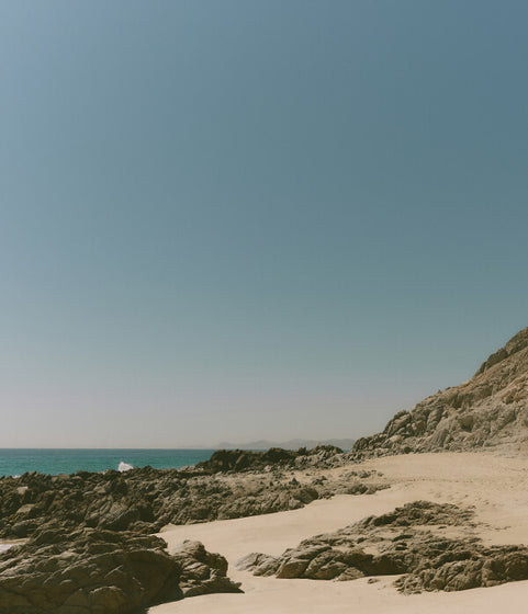 Beach with rocks and sand under a clear blue sky