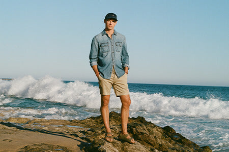 Man standing on a rocky beach with ocean waves in the background