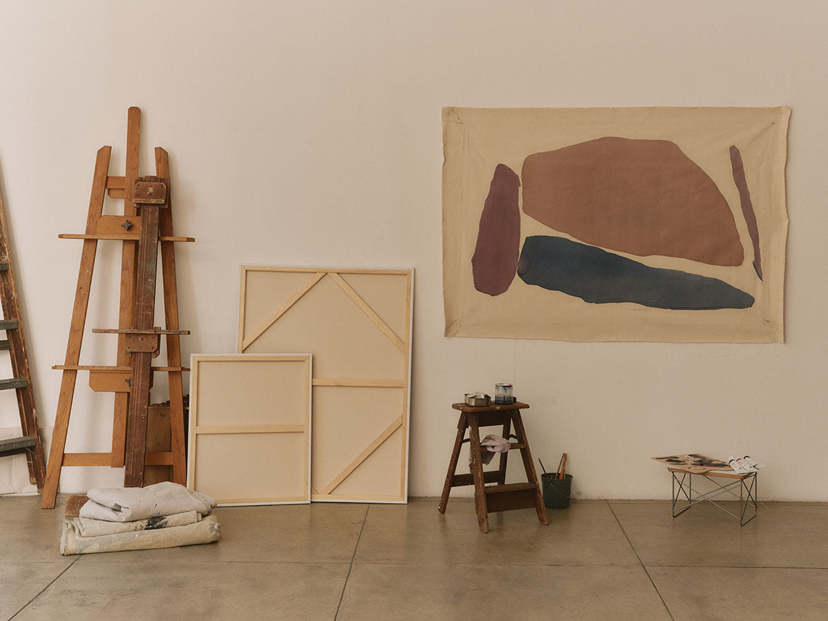 Art studio with easels, canvases, and abstract painting on the wall.