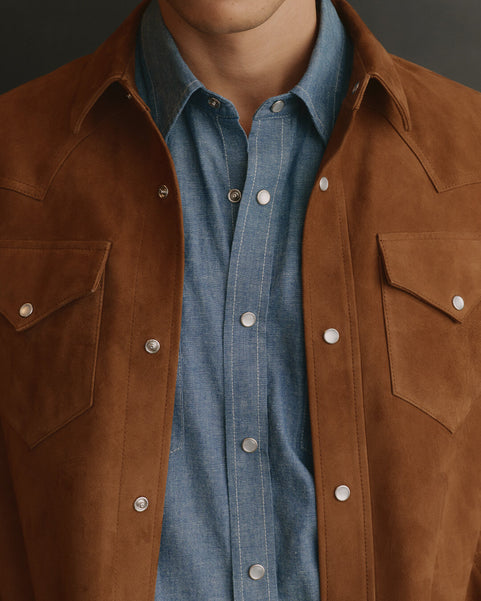 Brown suede jacket over a blue shirt on a mannequin against a dark background