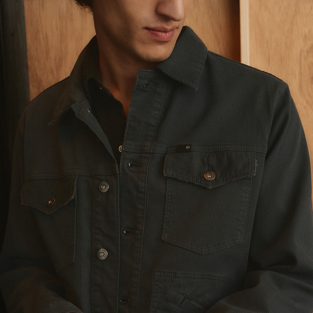 Person wearing a dark green jacket with a wooden background