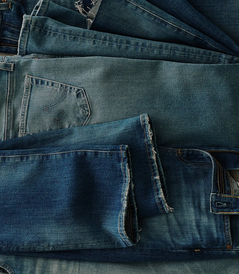 Stack of folded blue jeans with various shades.