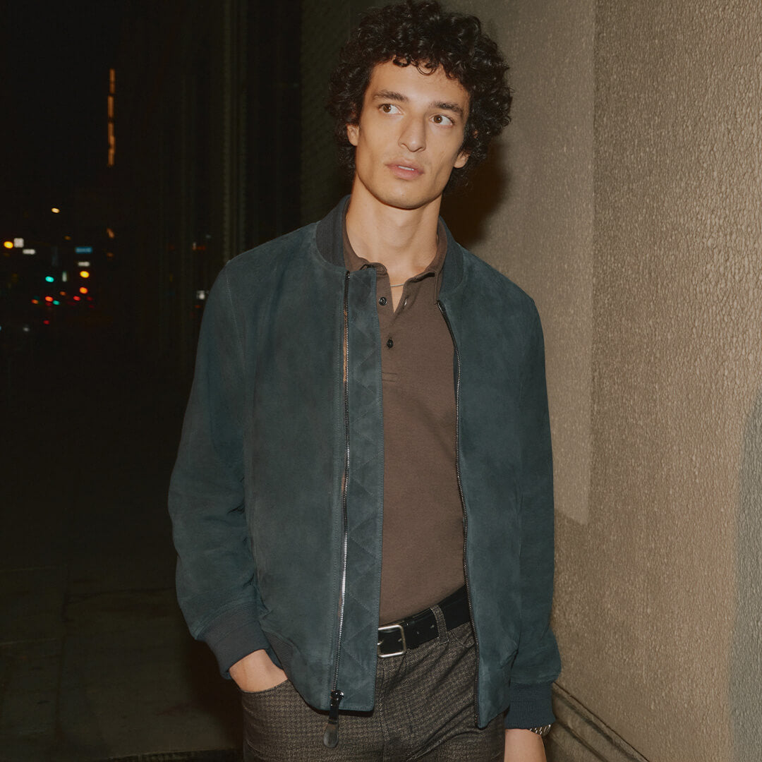 Man wearing a blue jacket standing against a dark background