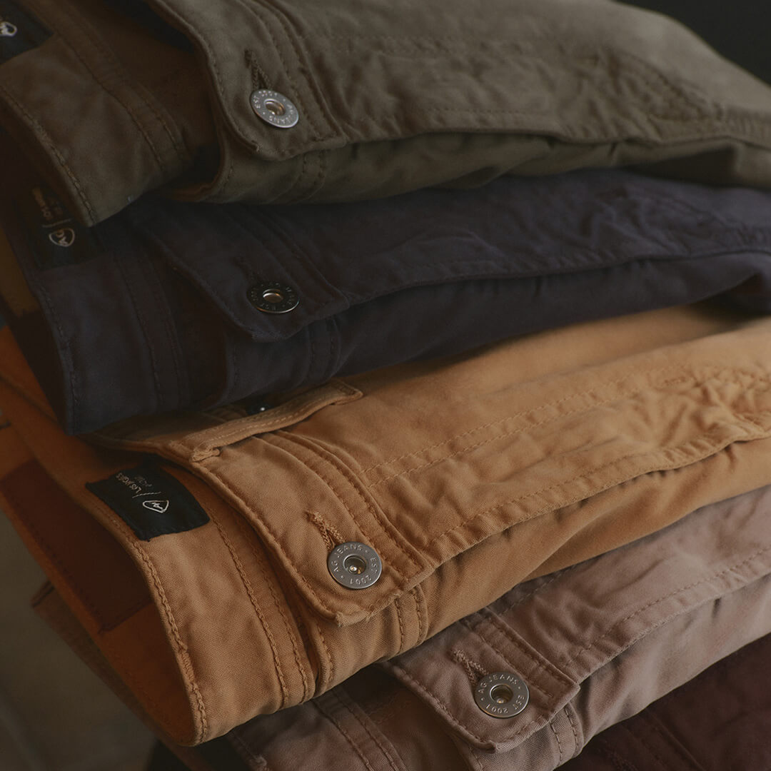 Stack of folded jackets in various colors on a dark background