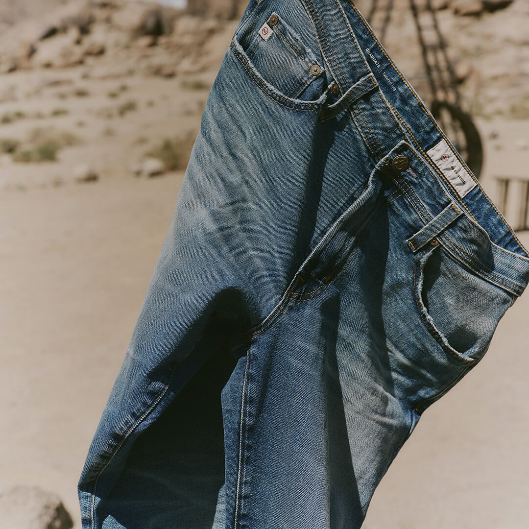 Blue jeans hanging on a wooden chair with a desert landscape in the background