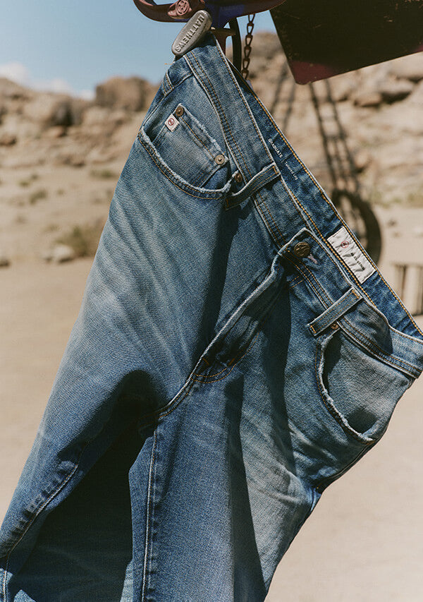 Blue jeans being held up against a desert background