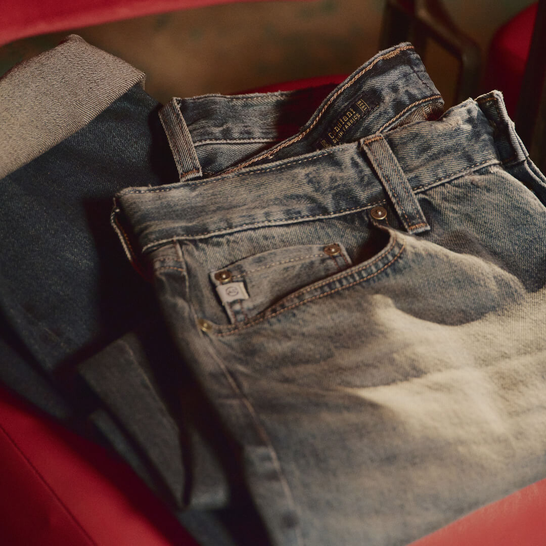 Folded blue jeans on a red surface
