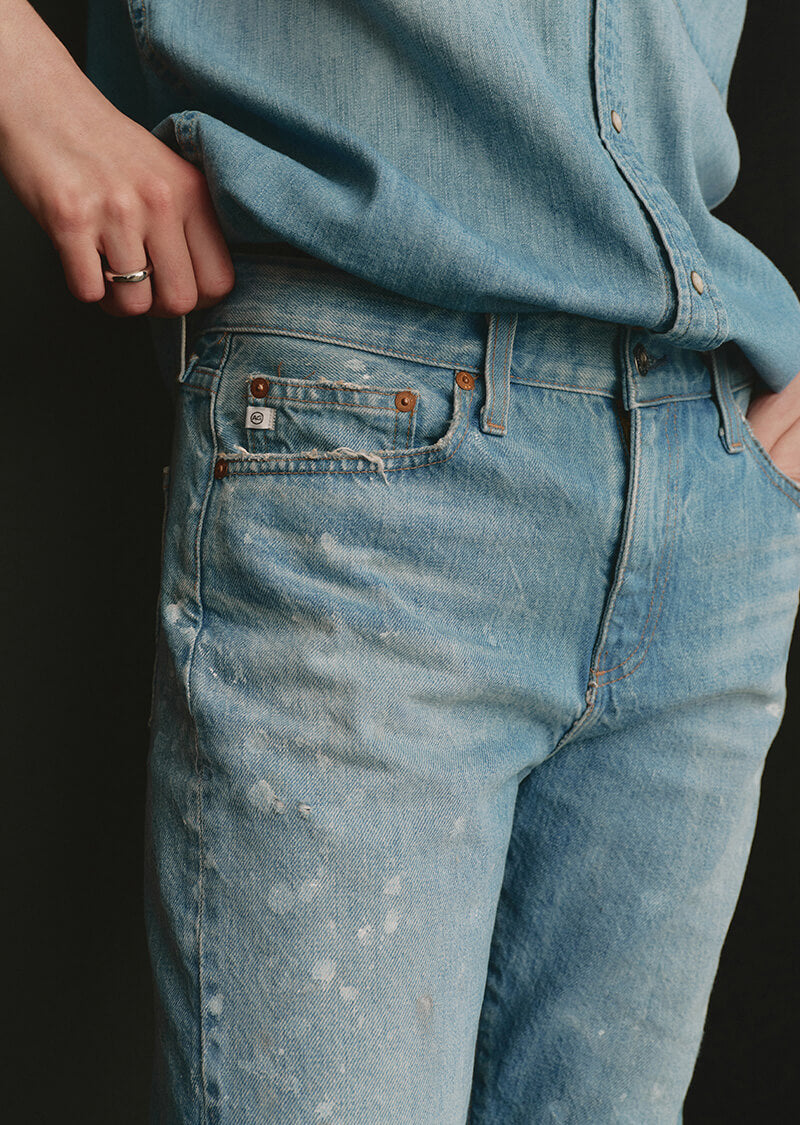 Close-up of a person wearing light blue jeans with a dark background
