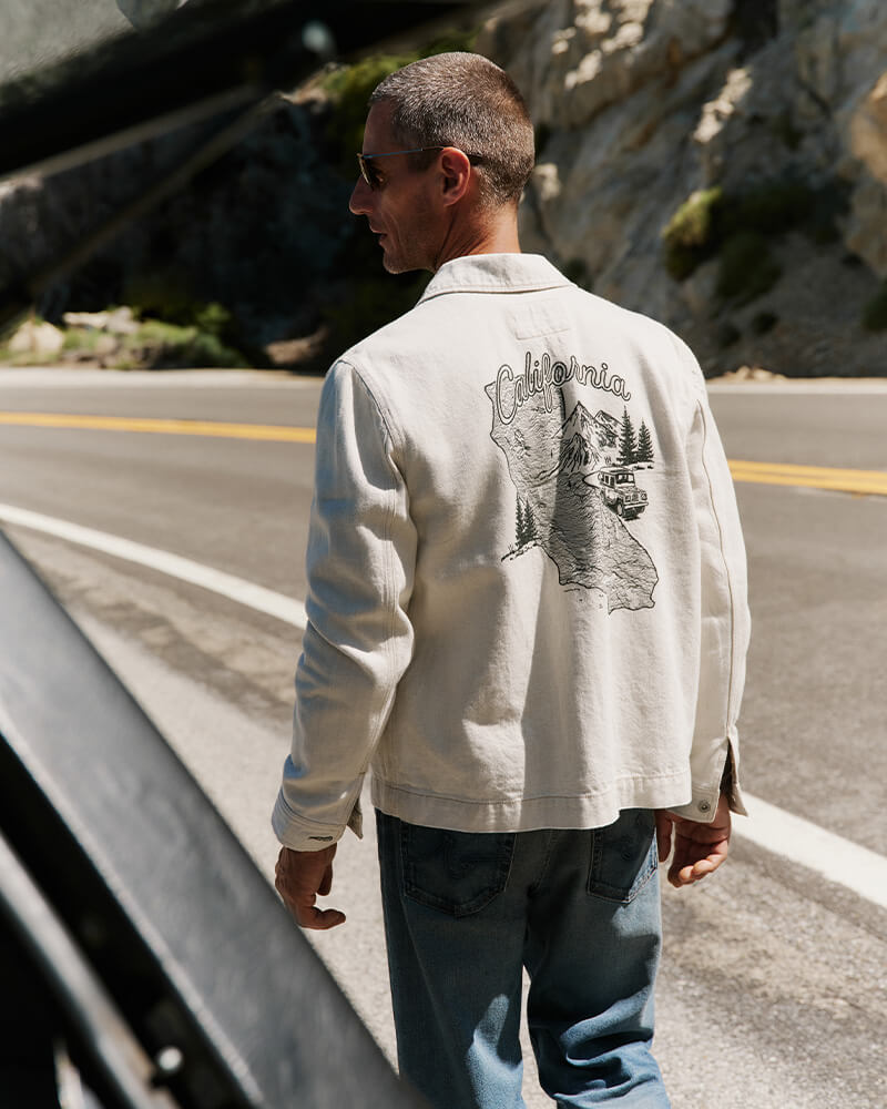 Man wearing a white jacket with 'California' design on a road