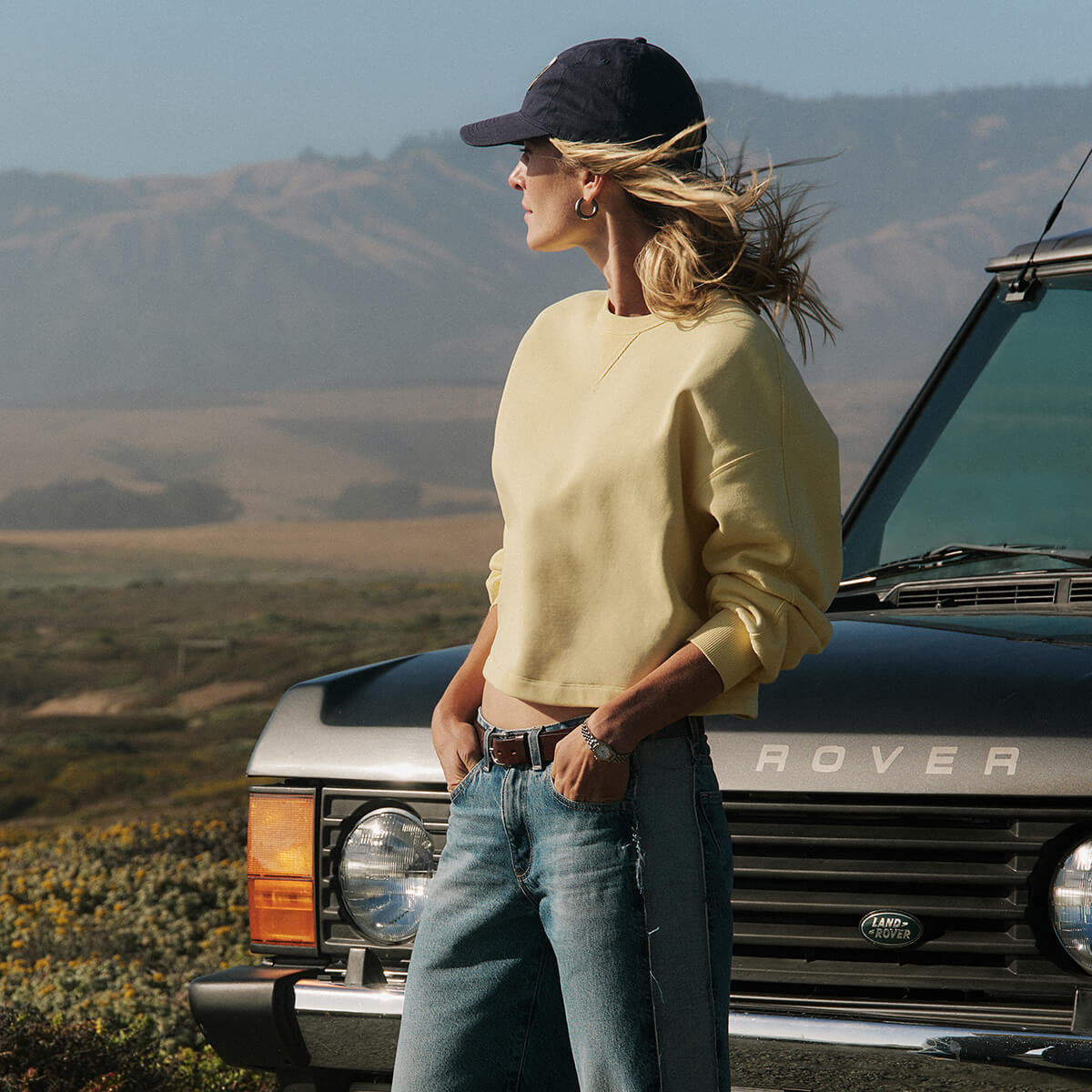 Person standing next to a Land Rover with mountains in the background