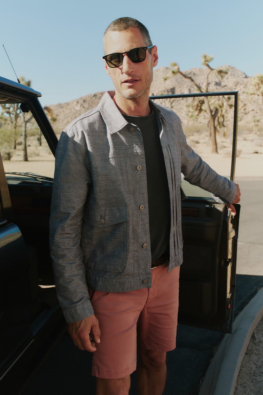 Man standing next to an open car door in a desert setting