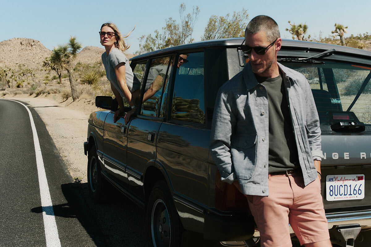 Two people standing by a car on a desert road