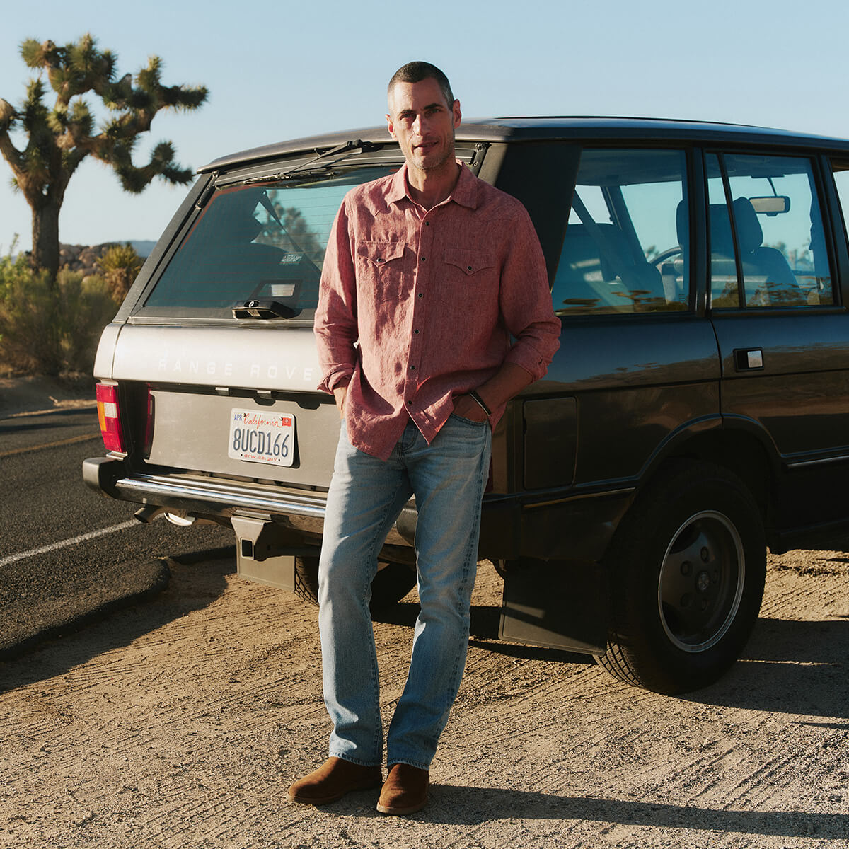 Man standing next to a vintage car in a desert setting
