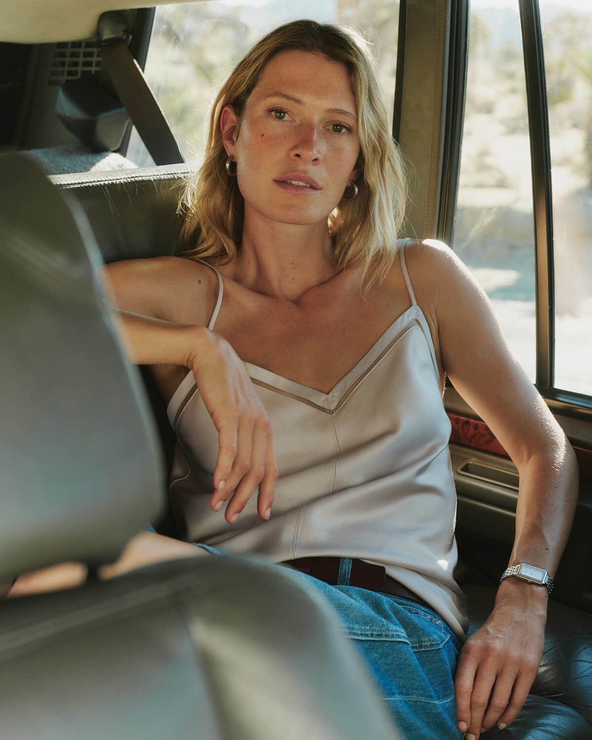 Woman sitting inside a vehicle with a desert landscape outside