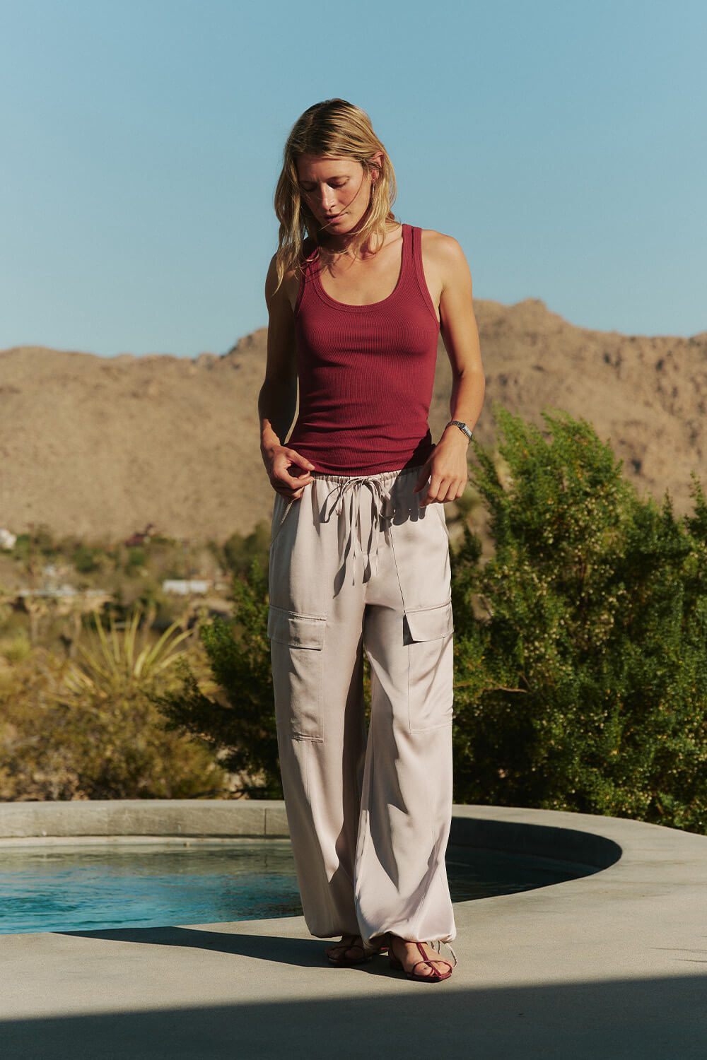 Woman standing by a pool with mountains in the background