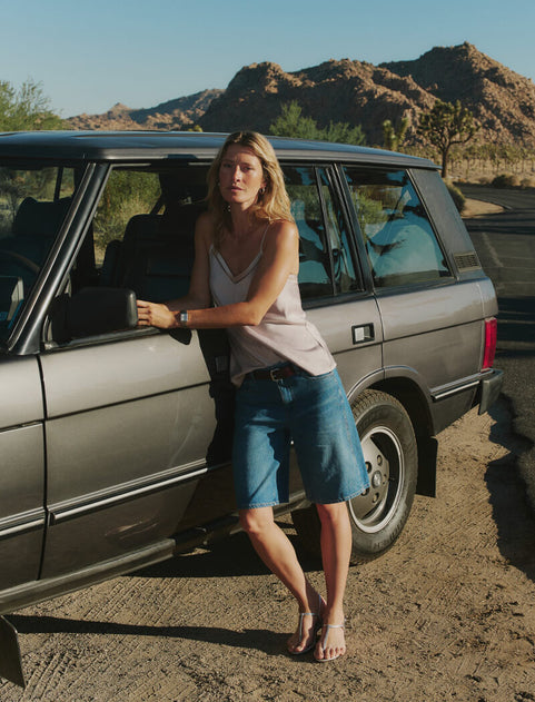 Woman standing next to a car in a desert setting