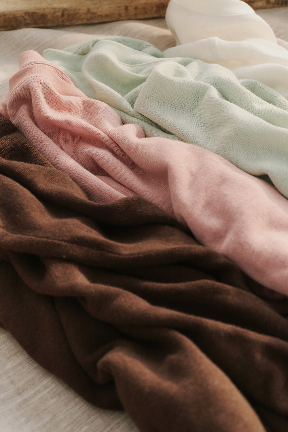 Stack of folded fabric in brown, pink, and green on a neutral background