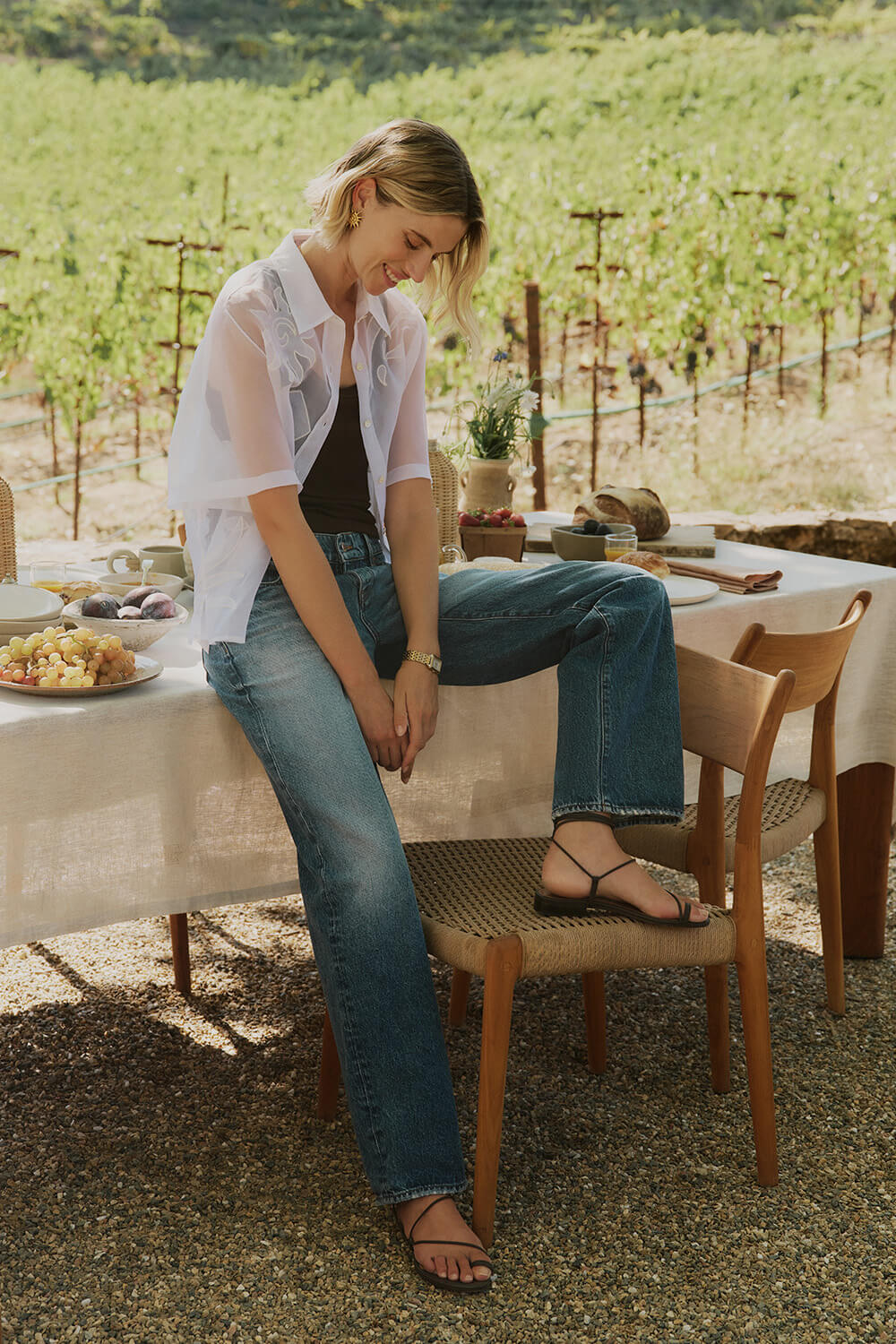 Woman sitting at a table in a vineyard setting