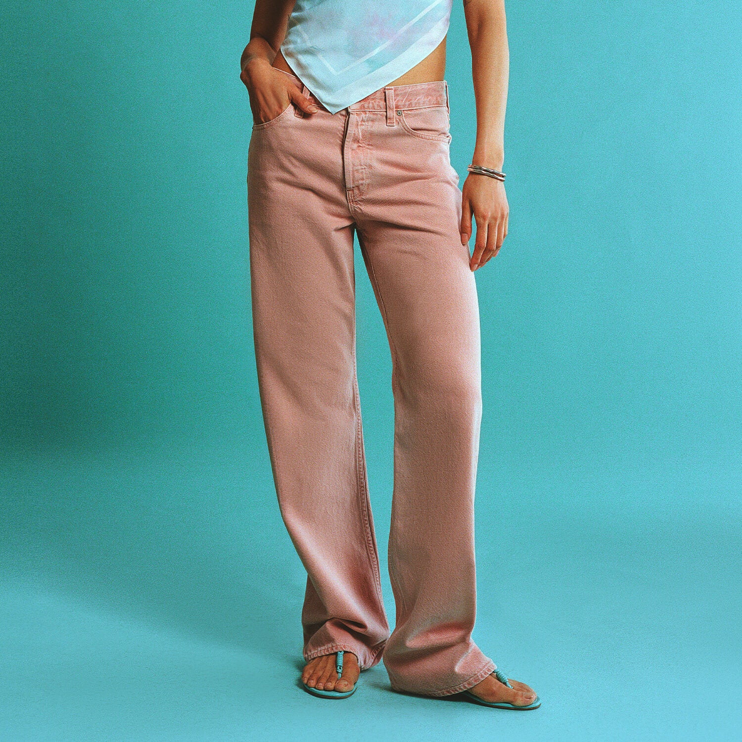 Person wearing pink pants against a teal background