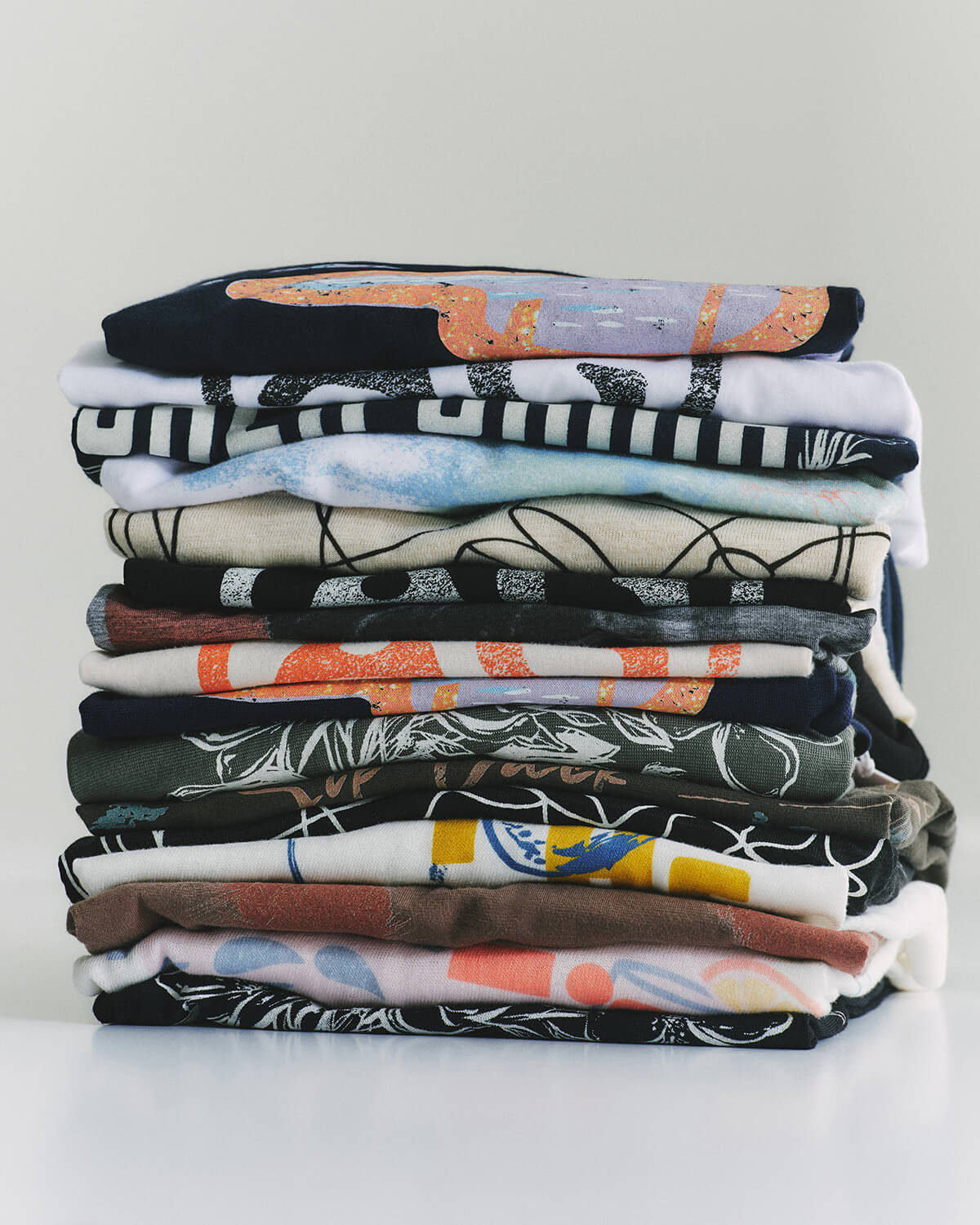 Stack of folded shirts with various patterns on a white background