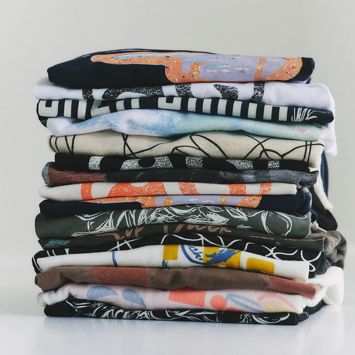 Stack of folded shirts with various patterns on a white background