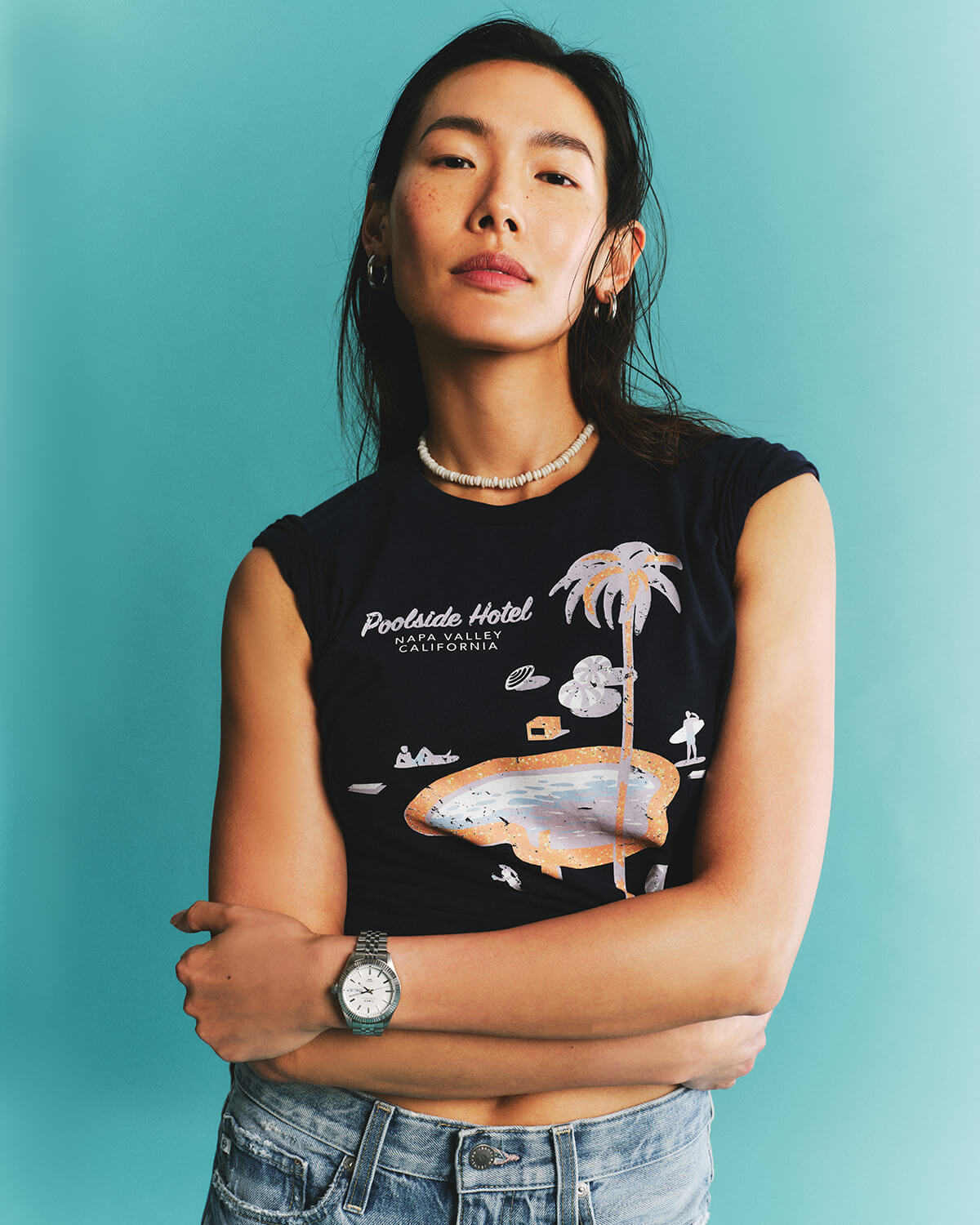 Person wearing a black sleeveless shirt with a graphic design against a teal background