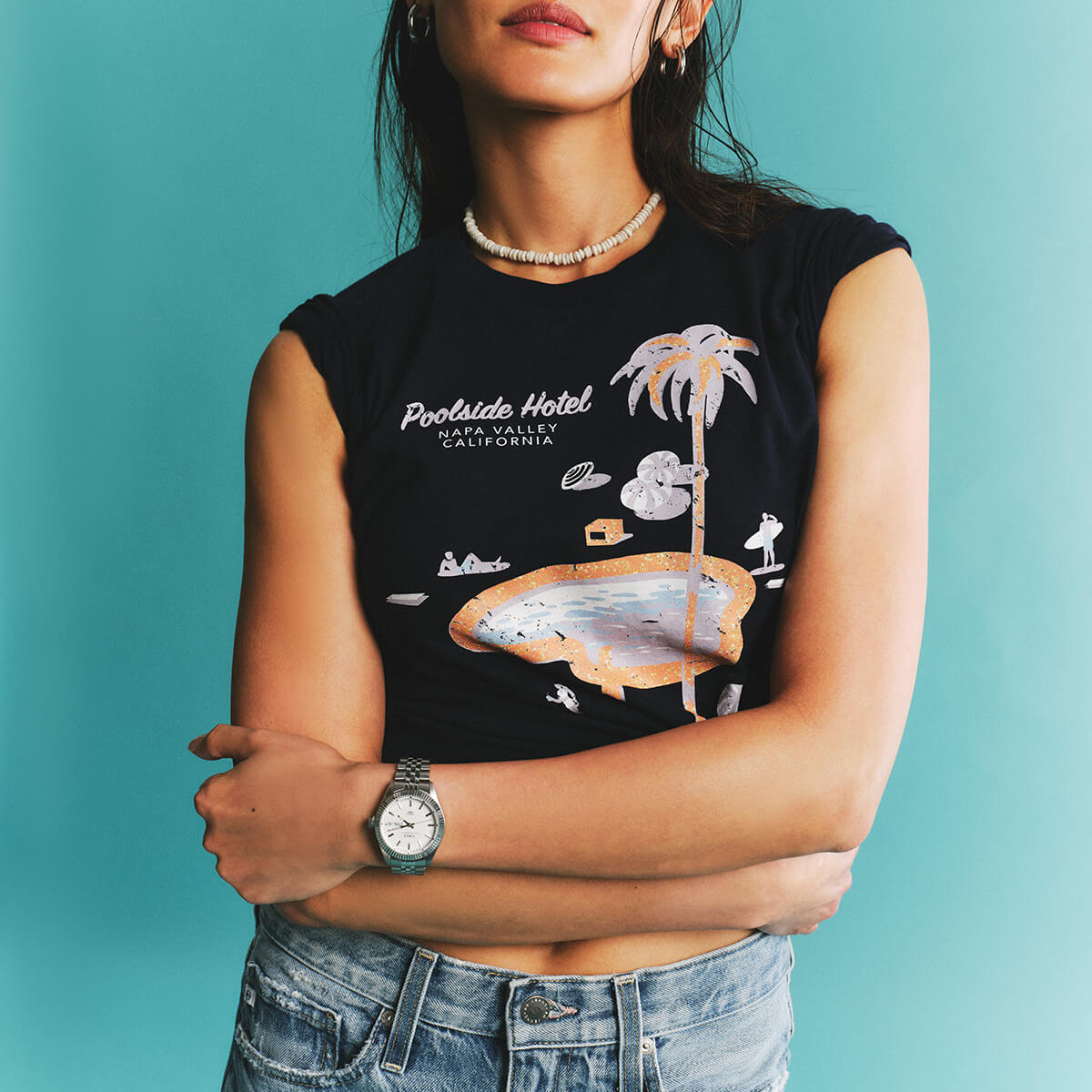 Person wearing a black sleeveless shirt with a graphic design against a teal background