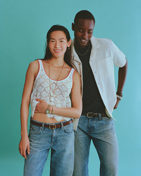Two people standing together against a teal background