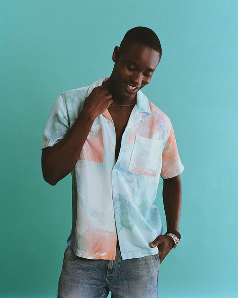 Man wearing a colorful shirt against a teal background