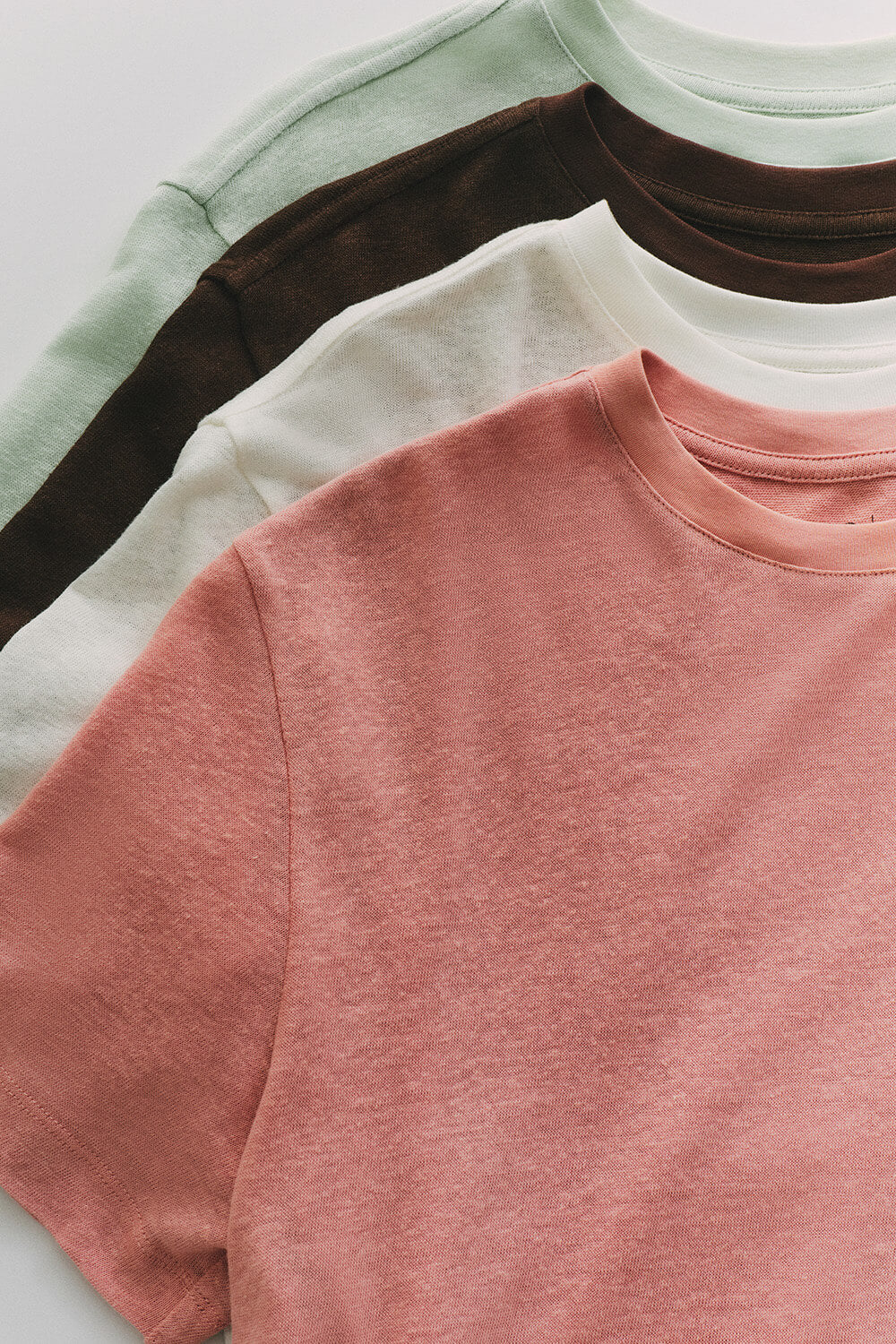 Stack of multicolored shirts on a light gray background