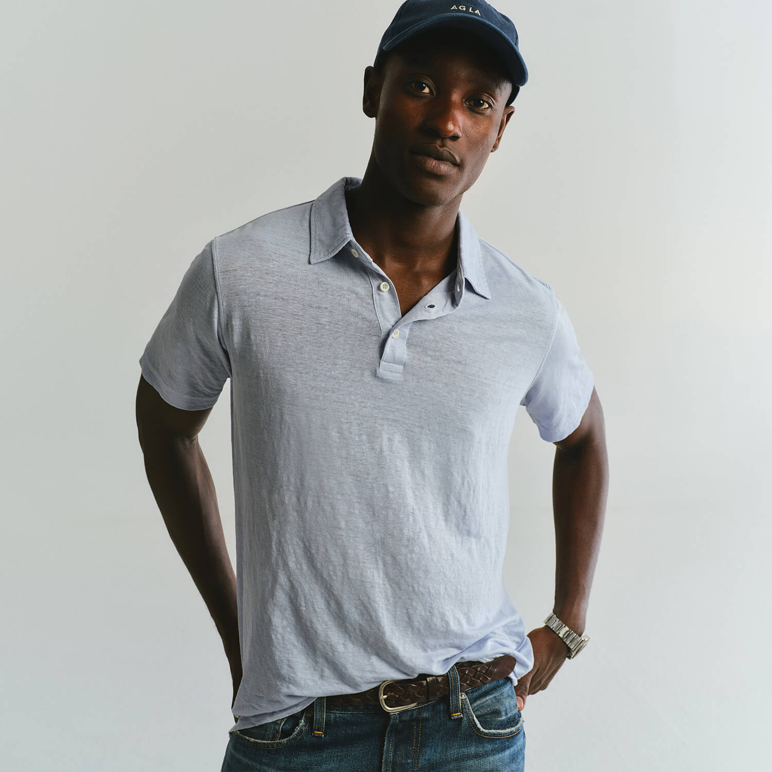 Man wearing a light gray polo shirt and blue cap against a plain background