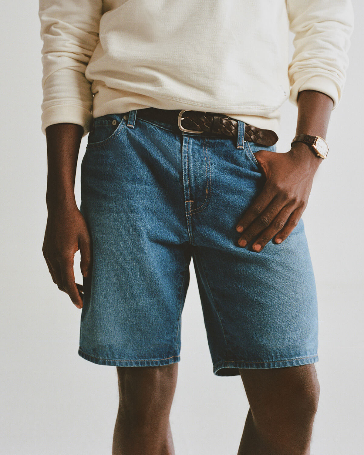 Person wearing blue denim shorts with a plain background