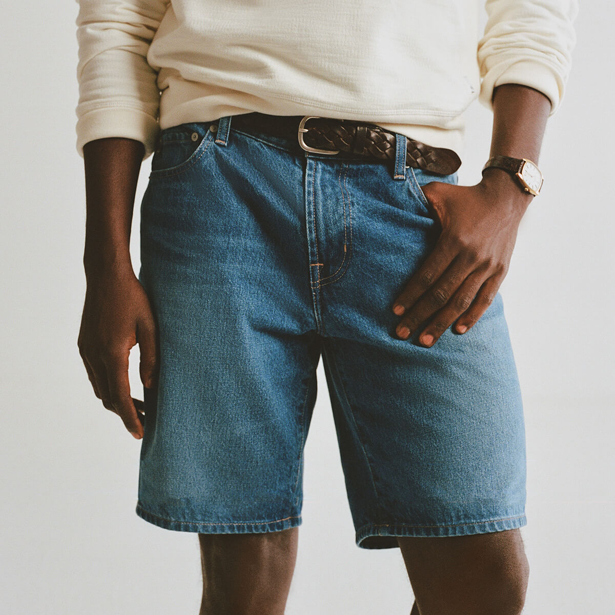Person wearing blue denim shorts with a plain background