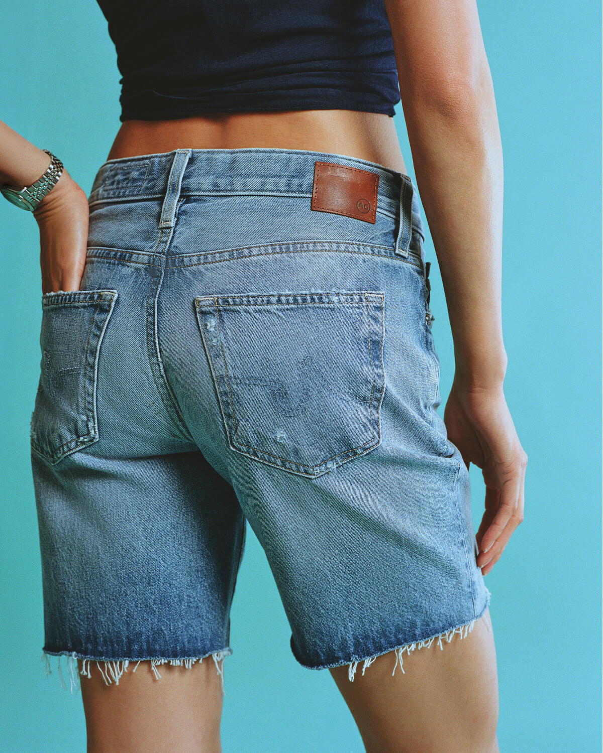 Person wearing blue denim shorts on a solid background