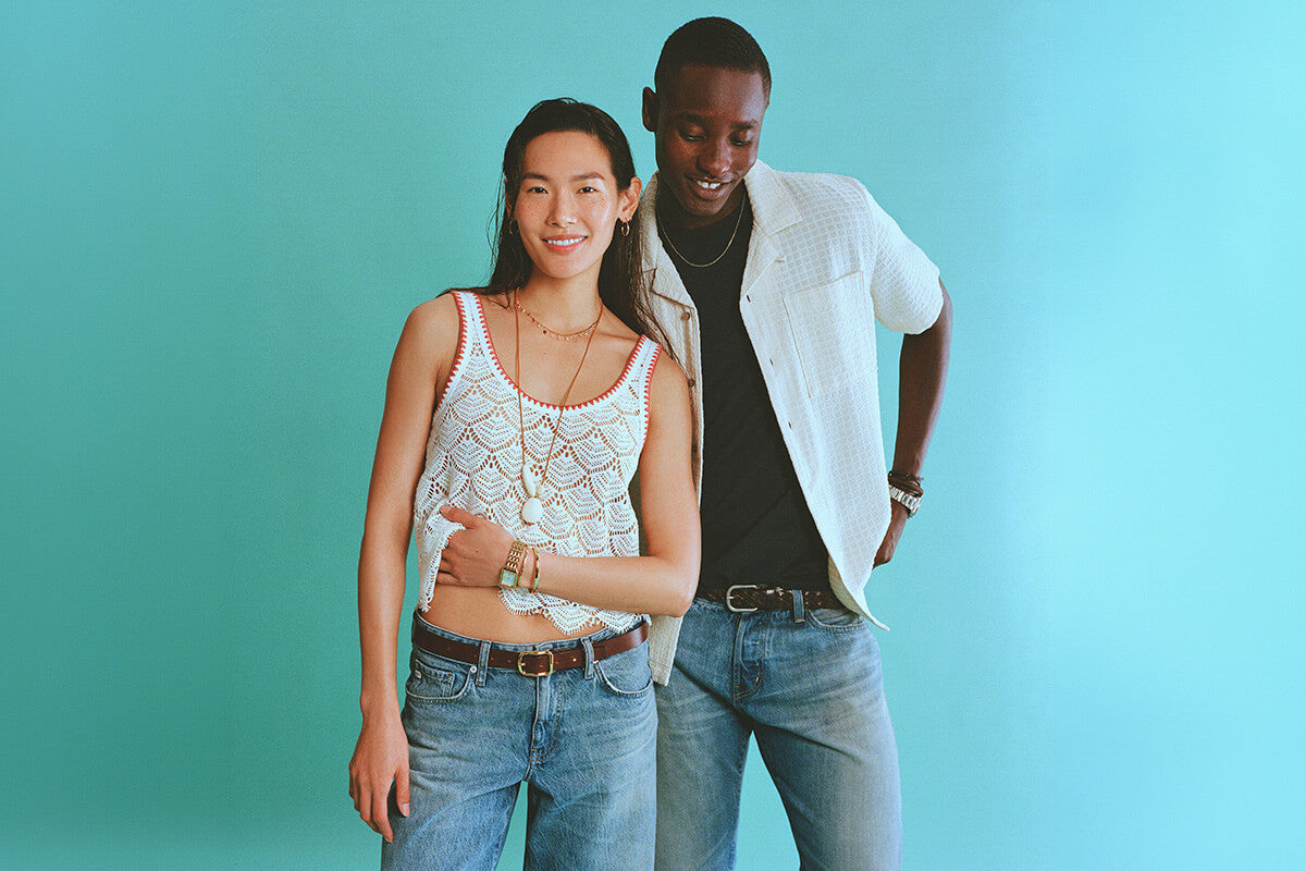 Two people standing close together against a teal background