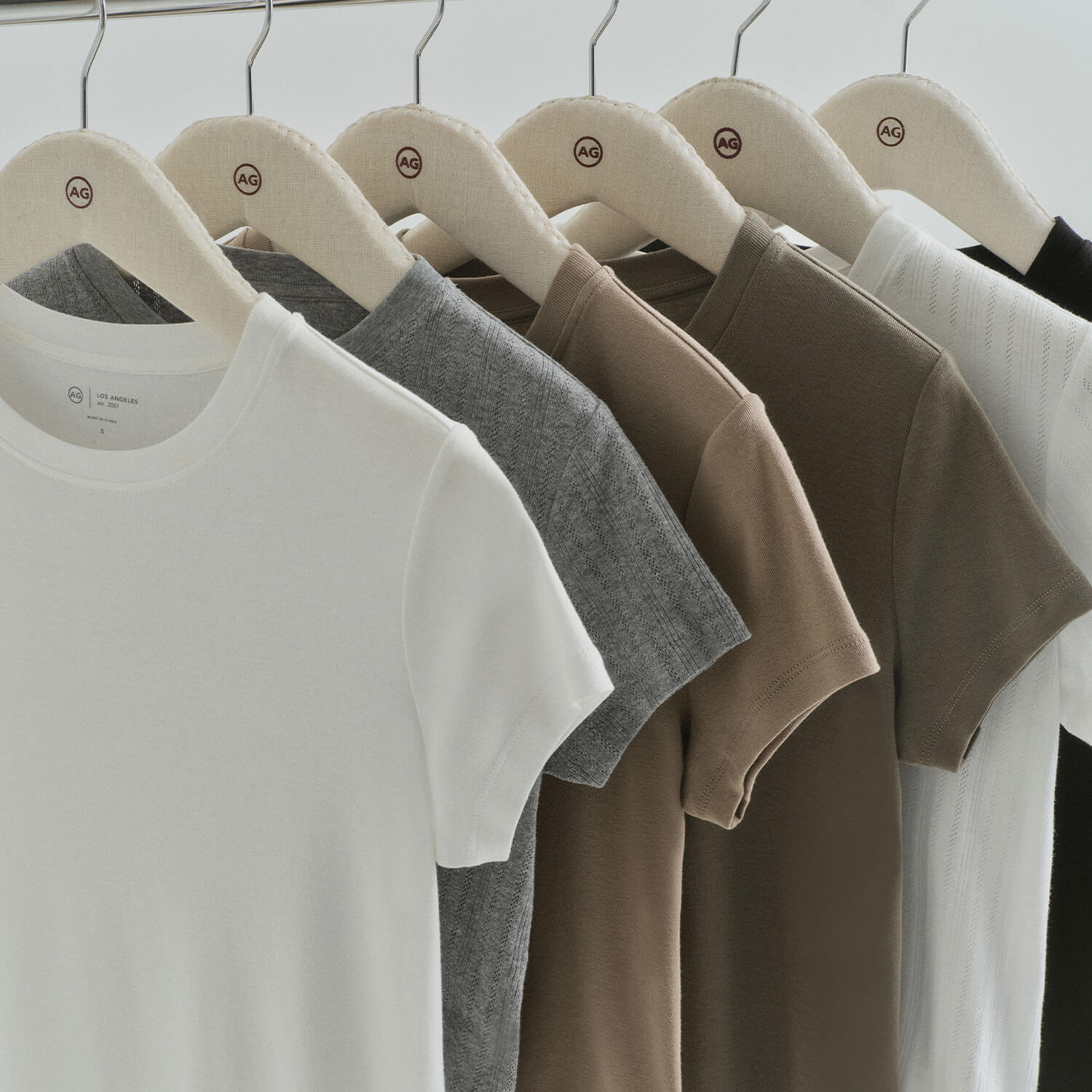 Row of plain t-shirts in various colors hanging on a rack.
