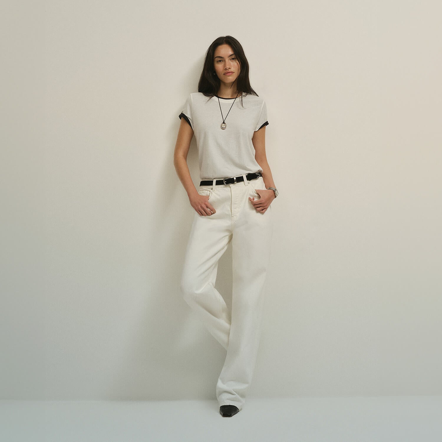 Woman wearing a white t-shirt and white jeans against a plain background for a monochromatic look.