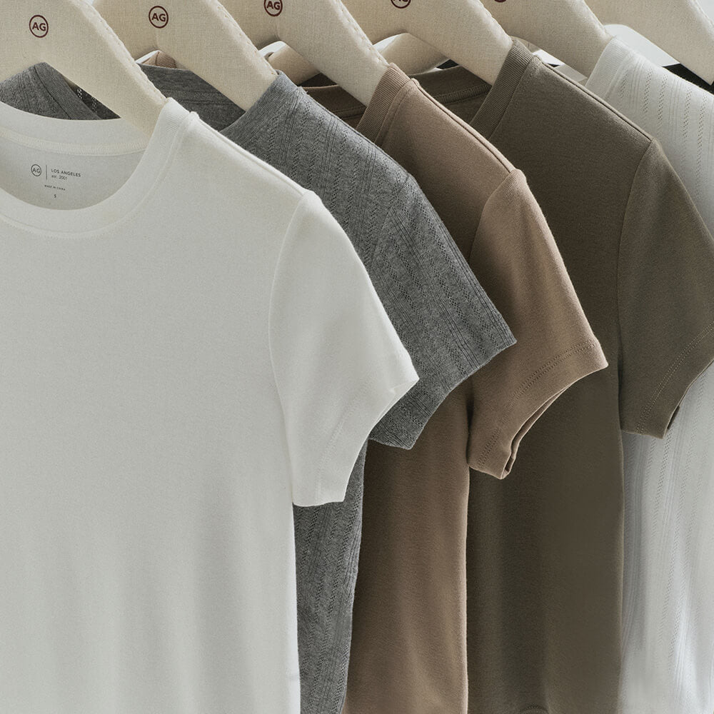Row of plain t-shirts on hangers against a white background