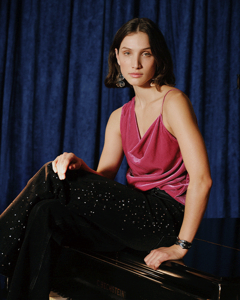 A split-screen lifestyle photograph featuring a woman in a pink top and black sequined pants sitting on a piano, and a man in a red jacket, denim shirt, and jeans standing in a studio with a blue curtain backdrop, microphone, and drums.