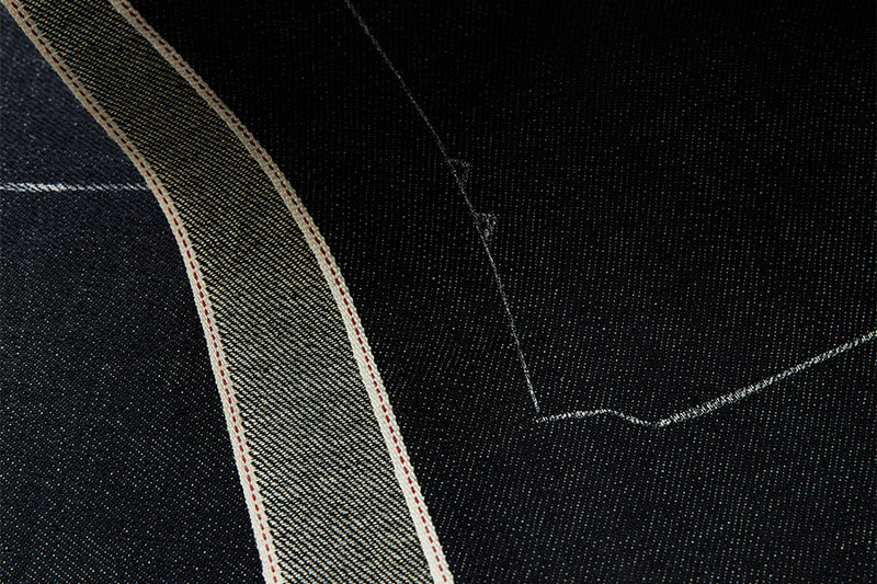 Close-up of black denim fabric with white stitching