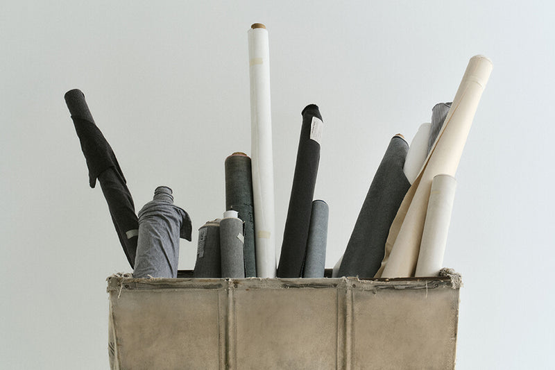 Collection of rolled-up papers in a wooden box against a light gray background