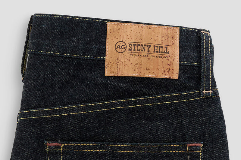 Dark blue jeans with a visible brand label on a light gray background