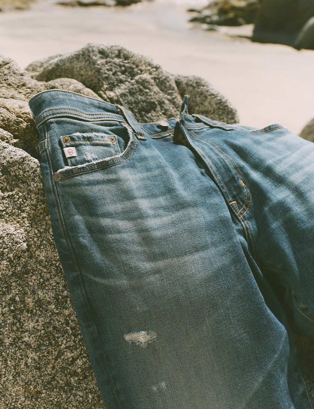 Faded jeans on top of boulder on the beach