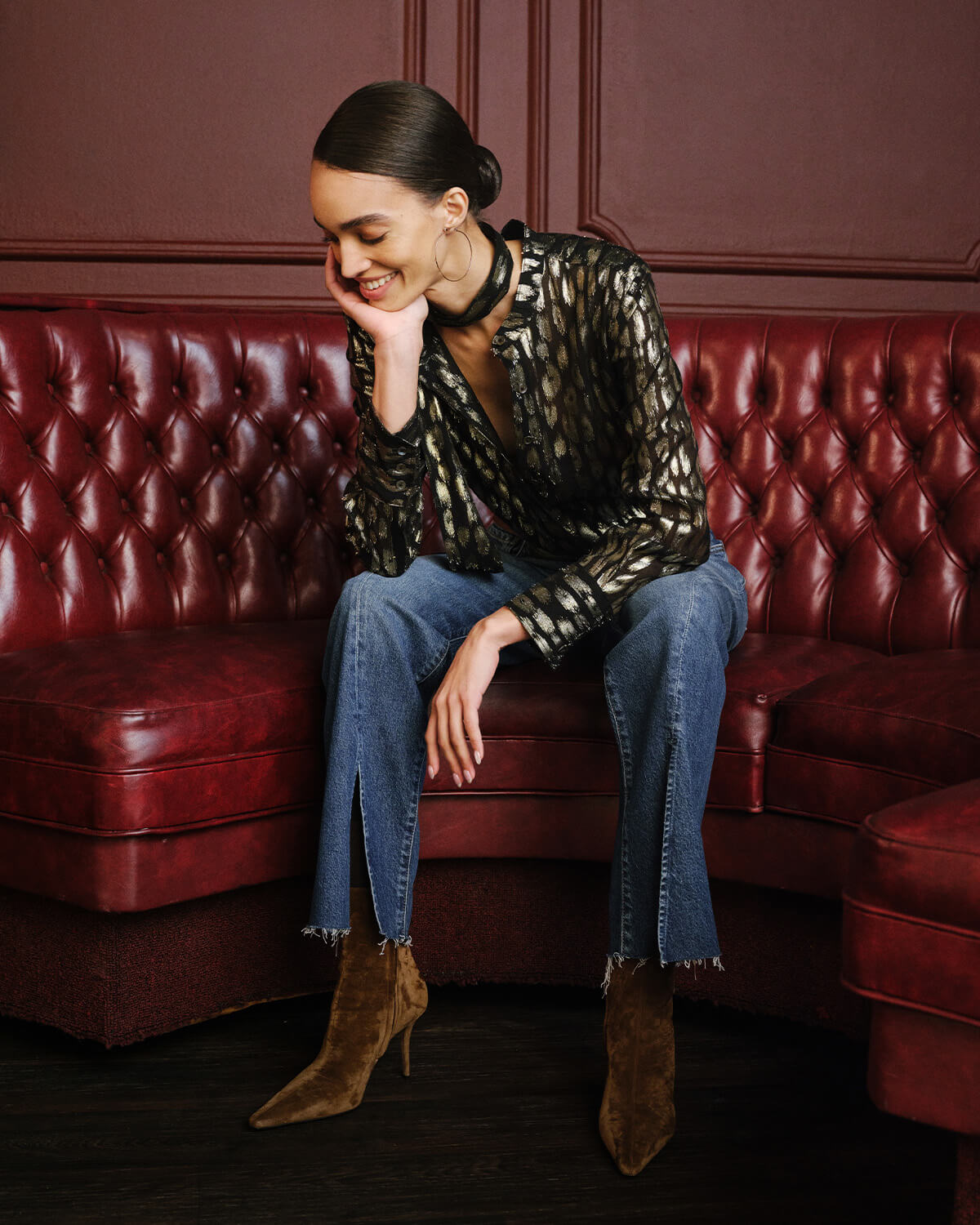 Woman wearing black and gold blouse with blue flare jeans